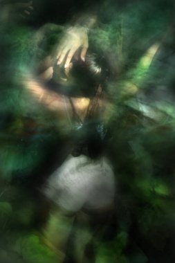 Begonya yeşilliklerinde duran genç bir kadın sanatçının bulanık hareketleri.