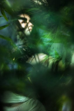 Hafif bulanık poz veren bir kadın rüyasında atmosferik sazlık yapraklarının arasına bakıyor..
