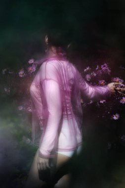 Estetik olarak yürüyen kadın elini Rosa Japon çiçeklerine uzatarak dolaşıyor..