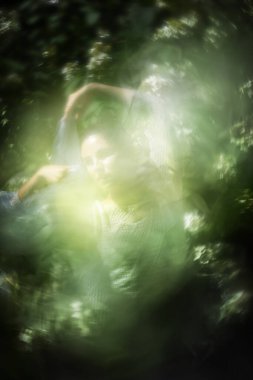 Canlı, bulanık bir hareketin içindeki kadın dansçının ruhani görünüşü Hortensiya çiçeklerine gömülür ve yaz sisinde beyaz bir duvak tutar..