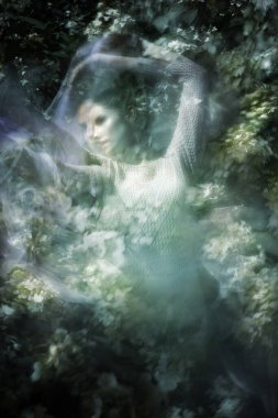 Çift pozlu hareket bulanıklığı örgü örmüş, beyaz peçeli, dairesel yönde hareket eden bir kadının enerjik dansı..