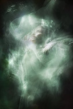 Beyaz bir peçe tutarken örgü örmüş, kurnazca hareket eden bir kadın dansçının birden fazla görüntüsü..