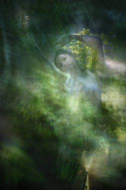 Yeşil orman yaprağı desenleri beyaz bir boho tarzı elbise giymiş bir kadın dansçının etrafında düzenlenir..