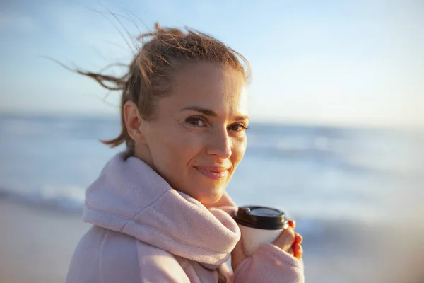 40岁穿着舒适毛衣 晚上在海滩喝茶的快乐优雅的女人的画像 — 图库照片