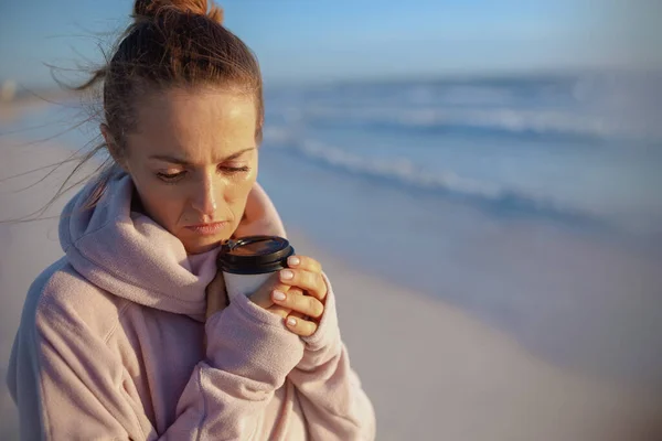 Zestresowana Nowoczesna Kobieta Średnim Wieku Przytulnym Swetrze Filiżanką Kawy Plaży — Zdjęcie stockowe