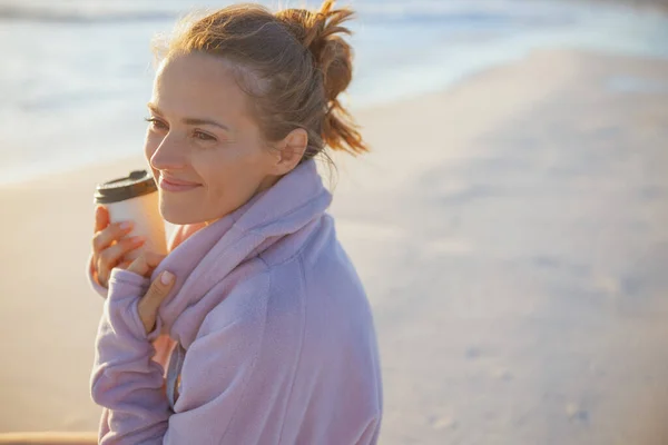 Szczęśliwa Nowoczesna Kobieta Średnim Wieku Przytulnym Swetrze Filiżanką Kawy Plaży — Zdjęcie stockowe