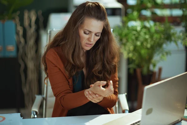 在现代绿色办公室里 带着笔记本电脑和手腕的不快乐的小企业主女人 — 图库照片