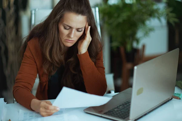 現代のグリーンオフィスで書類を扱うノートパソコンを持つエレガントな中小企業の所有者の女性を強調 — ストック写真