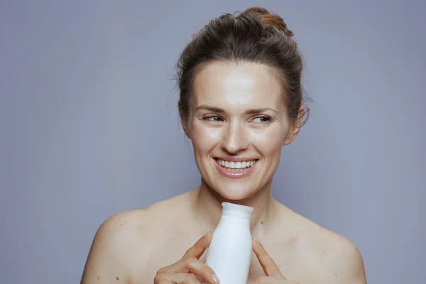 青空に孤立した化粧品クリーム瓶で笑顔の若い女性 — ストック写真