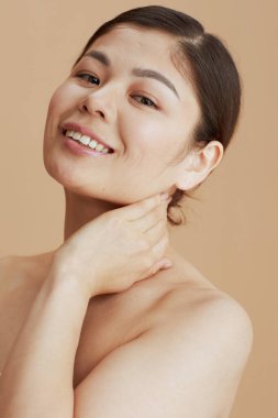 young asian woman looking in camera on beige background. clipart