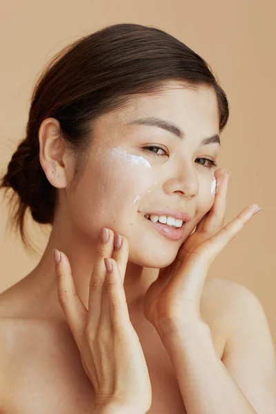 Junge Asiatische Frau Mit Gesichtscreme Gesicht Vor Beigem Hintergrund — Stockfoto