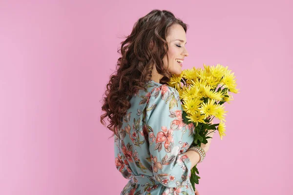幸せなスタイリッシュな女性とともに長い波状ブルネット髪とともに黄色菊の花ピンクの背景に孤立 — ストック写真