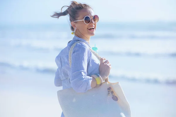笑容满面的现代女性 头戴白色草袋 在海滩畅饮 — 图库照片