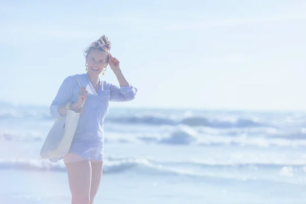快乐时尚的40岁女人 沙滩上放着白色草袋 — 图库照片