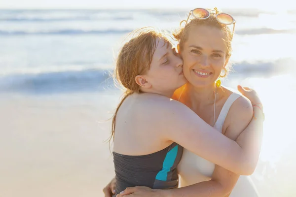 身穿泳衣的现代母亲和少女在海滩拥抱的画像 — 图库照片