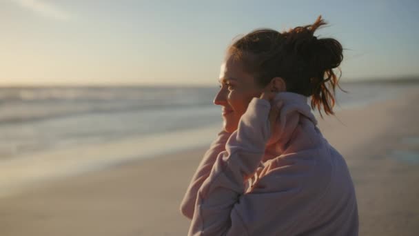 40歳のエレガントな女性がリラックスしてビーチで居心地の良いセーターを着て — ストック動画