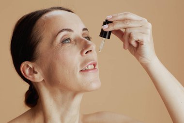 modern woman with cosmetic elixir against beige background.