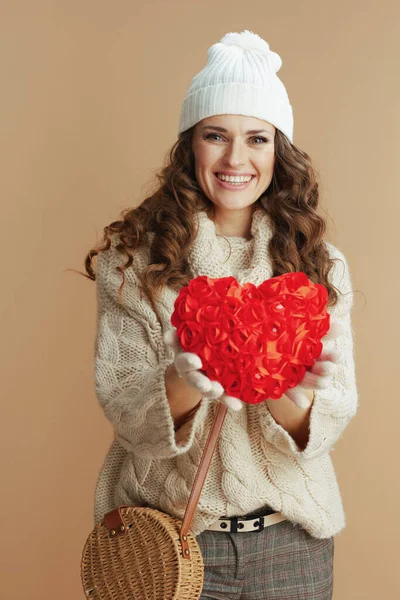 米色毛衣 手套和帽子与红心手提包米色背景相映衬的快乐现代女性画像 — 图库照片