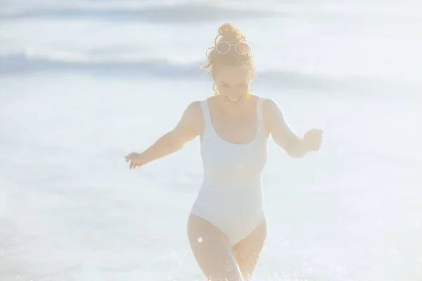楽しい時間を過ごすビーチで白い水着のエレガントな女性を笑顔 — ストック写真
