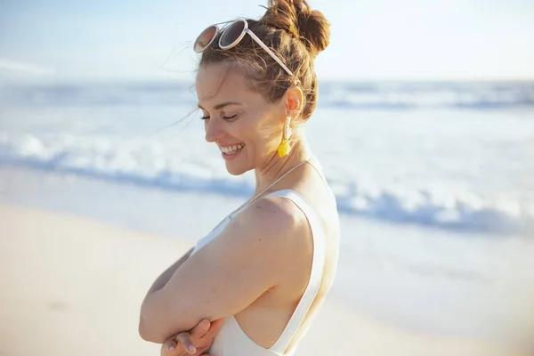ビーチでリラックスした白い水着の幸せなスタイリッシュな女性 — ストック写真