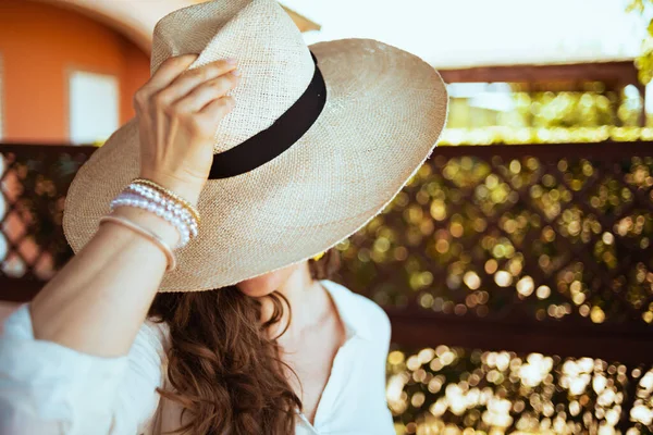 elegant female in white shirt with hat in the terrace of guest house hotel.
