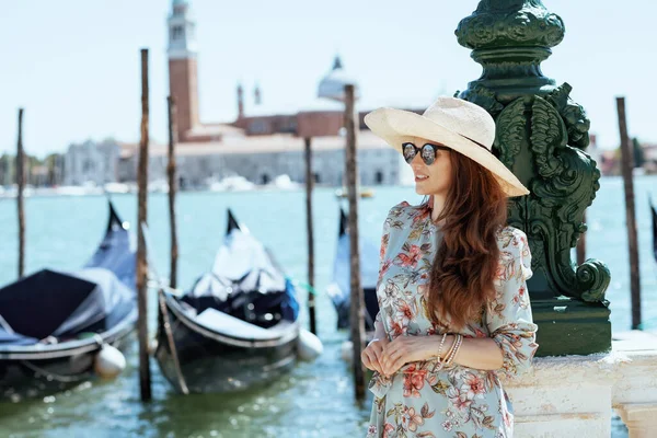 現代的な中年の旅行者の女性サングラスと帽子を持つ花のドレスヴェネツィア イタリアの堤防上の遠足 — ストック写真