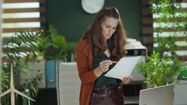 現代のグリーンオフィスで書類を扱うノートパソコンを持つ若い中小企業経営者の女性 — ストック動画