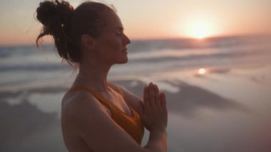 Rahatlamış fitness kadın koşu kıyafetleri ile spor takip cihazı ile gün batımında plajda neşe içinde.