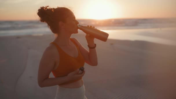 Ταιριάζει Αθλητική Γυναίκα Ρούχα Γυμναστικής Στην Παραλία Βράδυ Πόσιμο Νερό — Αρχείο Βίντεο