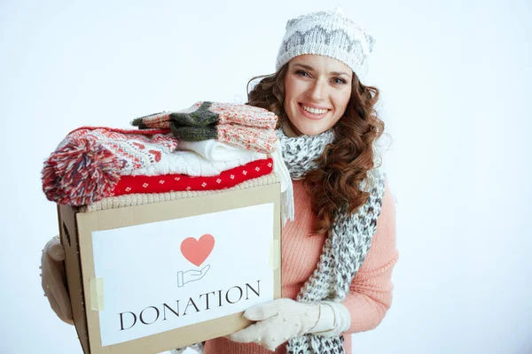 Hello winter. smiling trendy woman in sweater, mittens, hat and scarf isolated on white background with donation box.