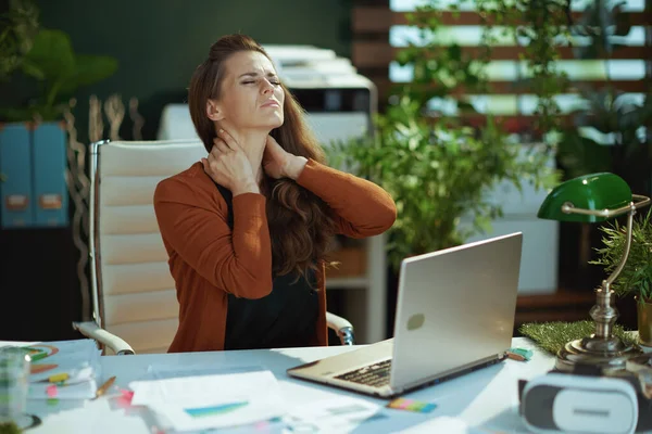 在现代的绿色办公室里 一个带着笔记本电脑和脖子的不快乐优雅的小企业主女人 — 图库照片