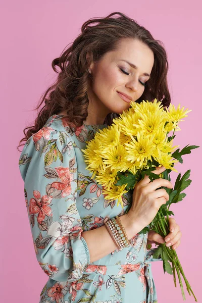 淡定的现代女性 身穿花裙 开黄色菊花 背景为粉色 — 图库照片