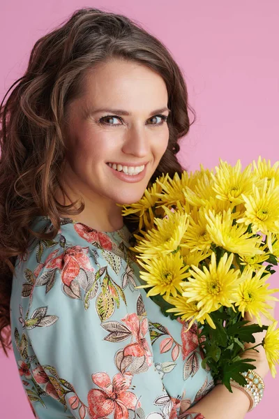 40岁的快乐女人的画像 一头长长的波浪般的黑发 黄色菊花 背景是粉红色的 — 图库照片
