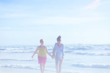 Mutlu modern anne ve çocuk sahilde yürüyor..