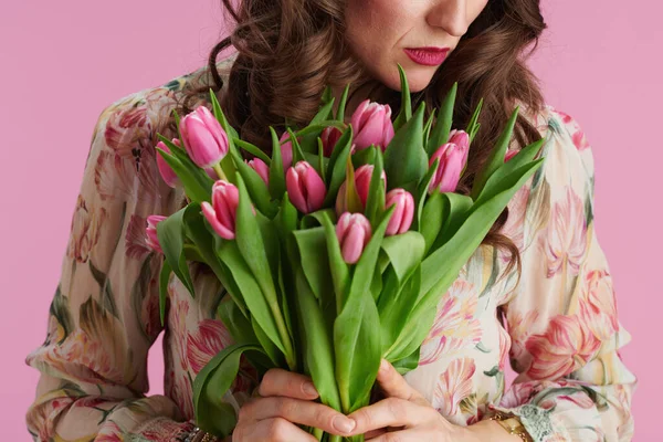 Closeup on woman with tulips bouquet isolated on pink.