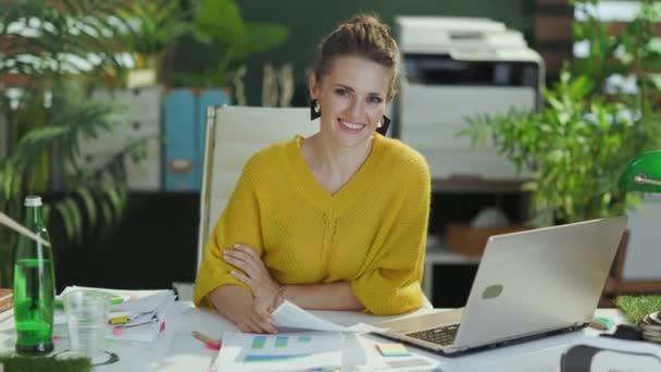 現代の緑のオフィスで文書を扱う黄色のセーターでスタイリッシュな中年中小企業所有者の女性を笑顔 — ストック動画