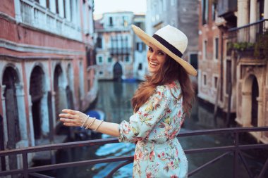 Venedik, İtalya 'da gezintiden keyif alan çiçekli elbiseli mutlu orta yaşlı gezgin kadın..