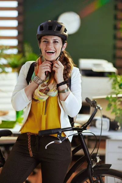 happy elegant business woman in bike helmet with bicycle in modern eco office.