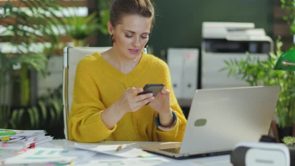 スマートフォンで黄色のセーターで流行の中小企業経営者の女性を笑顔 — ストック動画
