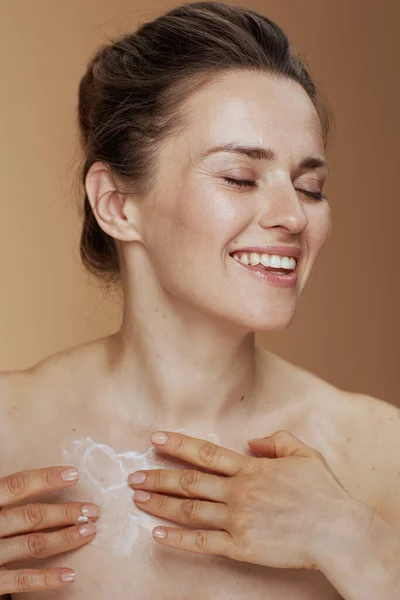 Smiling Modern Middle Aged Woman Rubbing Body Cream Beige Background — 图库照片