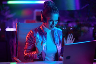 Neon metaverse futuristic concept. smiling modern business woman with laptop and headset having video call in modern office.