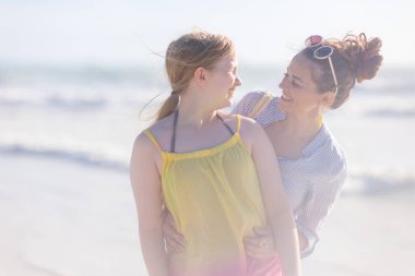 smiling modern mother and child at the beach having fun time.