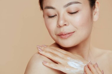 relaxed modern woman with hand cream on beige background.