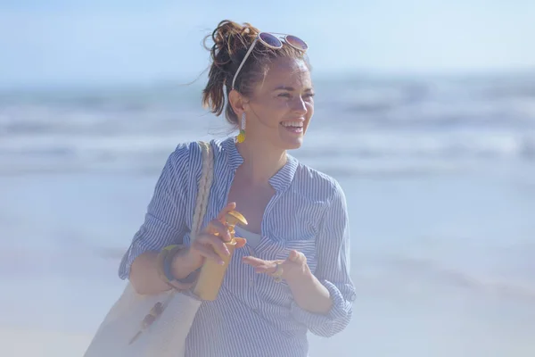 stock image happy elegant 40 years old woman with sunscreen and white straw bag at the beach.