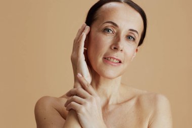 modern middle aged woman posing isolated on beige background.