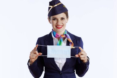 smiling elegant female flight attendant isolated on white background in uniform with medical mask.