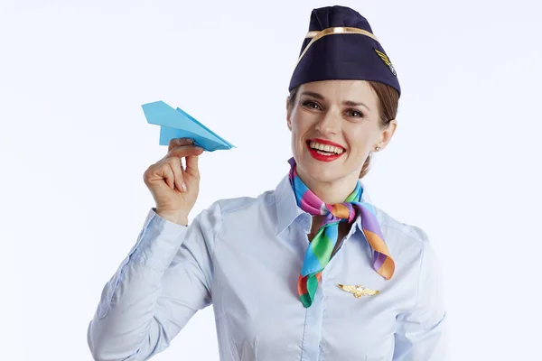happy stylish female flight attendant isolated on white background in uniform with paper airplane.