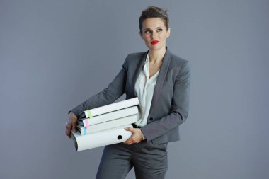 tired modern small business owner woman in gray suit with folders isolated on gray background.