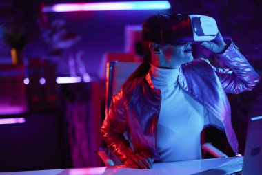 Neon metaverse futuristic concept. stylish woman in virtual reality goggles in modern office.
