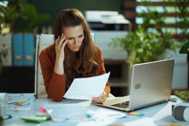 Modern yeşil ofisteki belgelerle uğraşan 40 yaşında, küçük bir iş kadını..